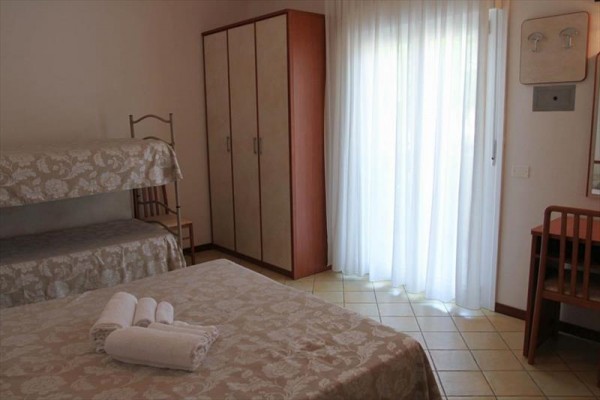 Pokój hotelowy z łóżkiem podwójnym i piętrowym, szafą i biurkiem.