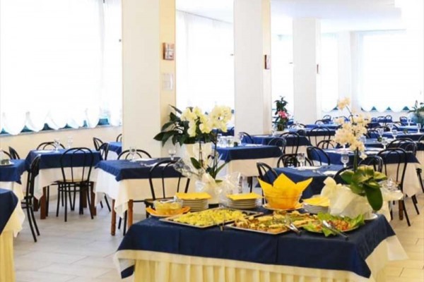 Restauracja z nakrytymi stołami pokrytymi niebiesko-białymi obrusami i bukietem na stole.