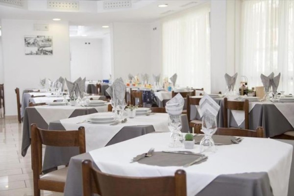 Elegancko nakryta restauracja z białymi i szarymi obrusami.