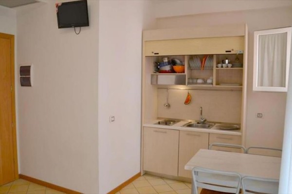 Mały aneks kuchenny z zlewem, stołem i krzesłami w rogu pomieszczenia.