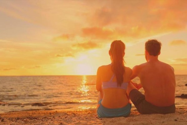 Para siedzi na plaży podczas zachodu słońca.