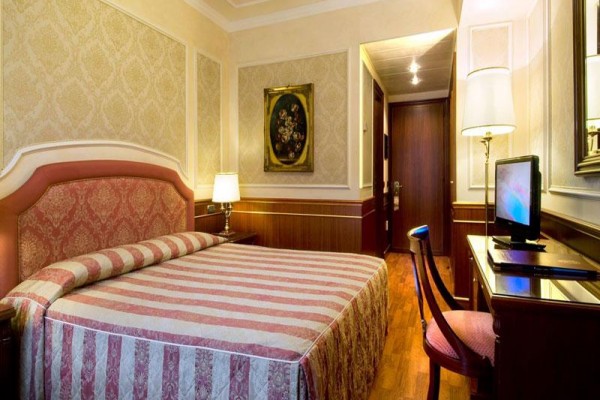 Elegancki pokój hotelowy z łóżkiem małżeńskim, obrazem na ścianie i telewizorem na stole.