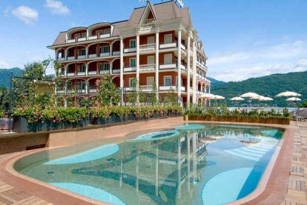Hotel z basenem na zewnątrz i górami w tle.
