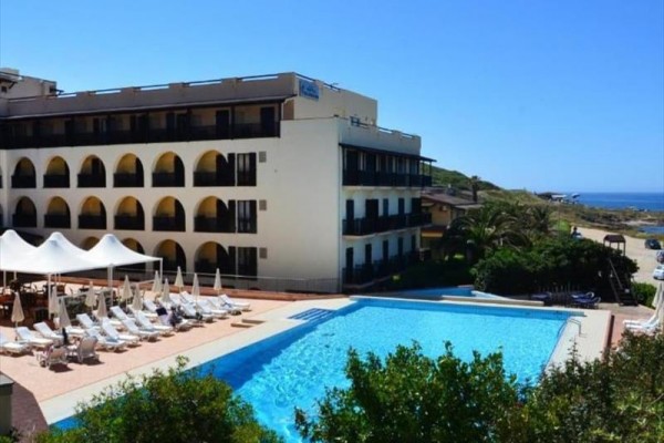 Kompleks hotelowy z basenem i leżakami nad morzem.