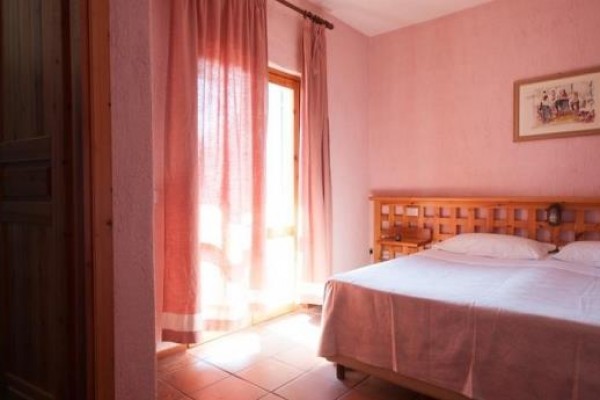 Sypialnia z podwójnym łóżkiem, różowymi ścianami i zasłonami obok łazienki.