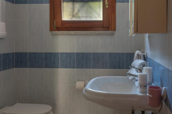 Łazienka z umywalką, toaletą i poziomym oknem na niebiesko-białych płytkach.