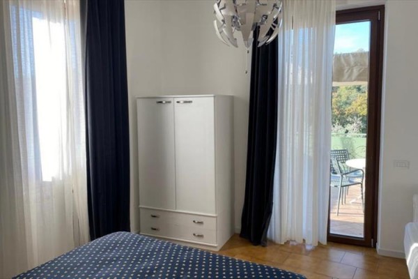 Sypialnia z łóżkiem, szafą i drzwiami prowadzącymi na balkon.