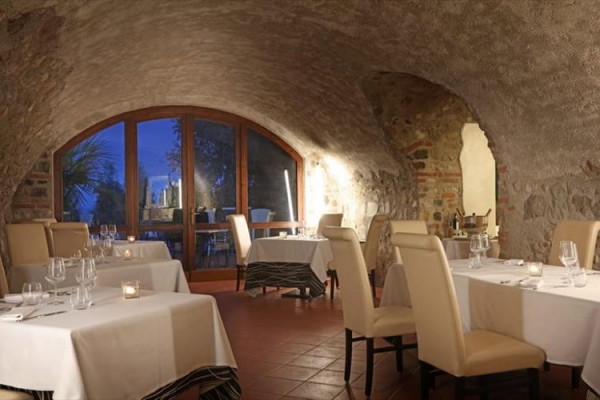 Restauracja w kamiennej piwnicy z białymi obrusami i zapalonymi świecami.