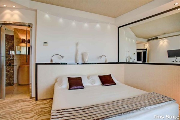 Nowoczesny pokój hotelowy z dużym łóżkiem i łazienką w tle.
