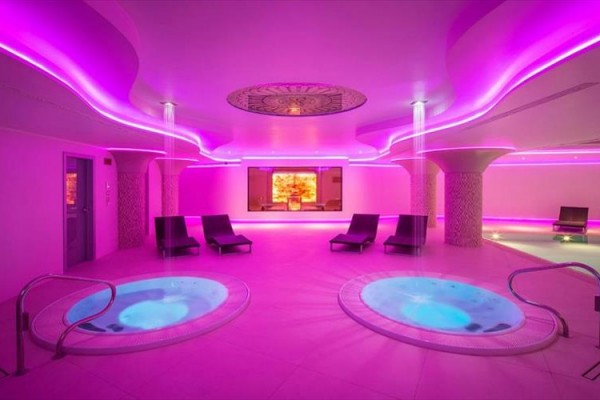Luksusowe centrum wellness z jacuzzi i różowym oświetleniem.