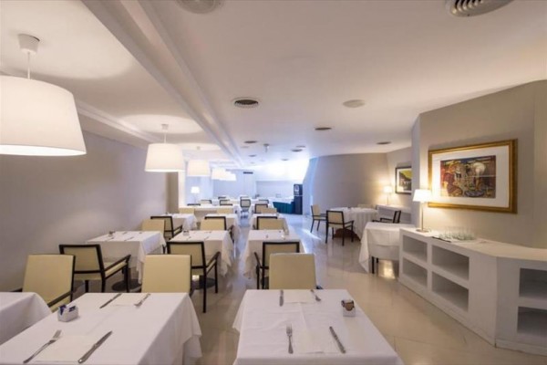 Elegancka restauracja z białymi obrusami i nowoczesnym oświetleniem.