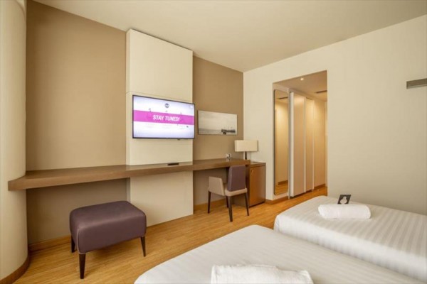 Nowoczesny pokój hotelowy z dwoma łóżkami, biurkiem i telewizorem.