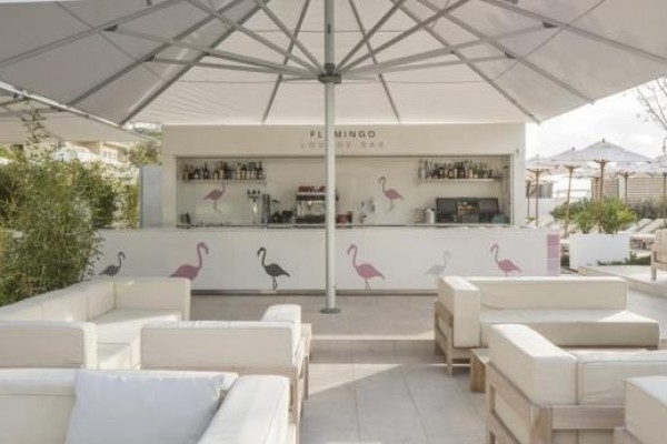 Zewnętrzny lounge bar z białymi sofami i dużymi parasolami.