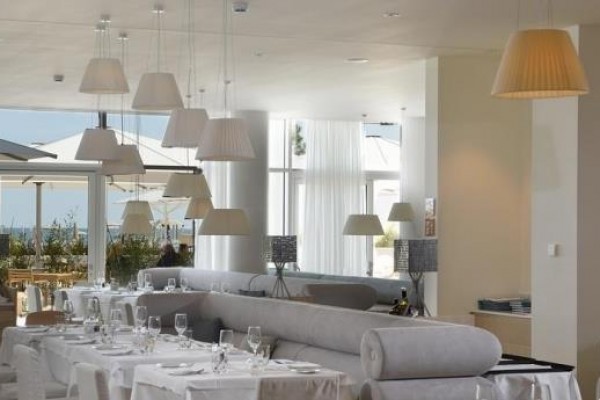 Elegancka restauracja z białymi obrusami i dużymi lampami.