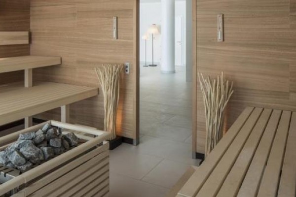 Nowoczesna sauna z drewnianymi ławami i pojemnikiem na kamienie.