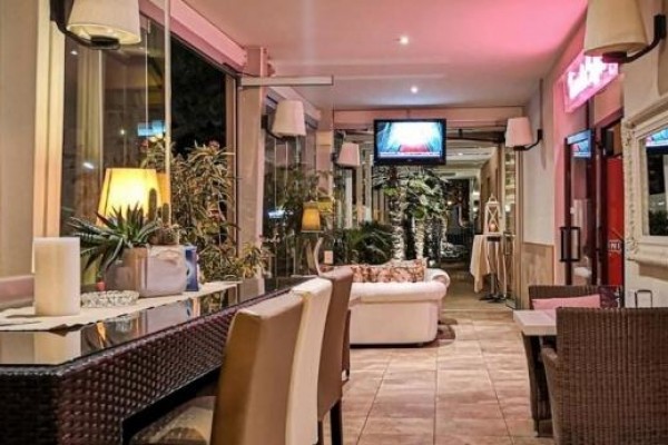Wnętrze nowoczesnej restauracji z stylowym miejscem do siedzenia i telewizorem na ścianie.