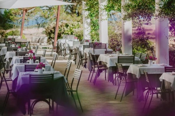 Zewnętrzny taras restauracji z elegancko nakrytymi stolikami i krzesłami.