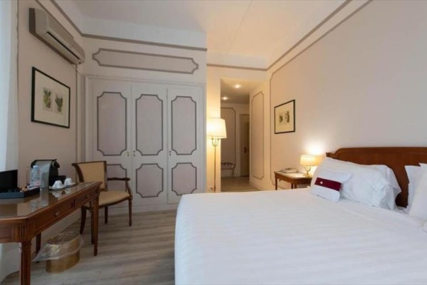Pokój hotelowy z łóżkiem małżeńskim, biurkiem i szafą.