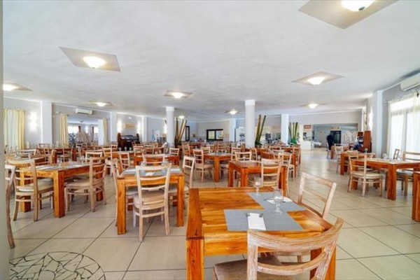 Przestronna restauracja z drewnianymi stołami i krzesłami w jasnym wnętrzu.