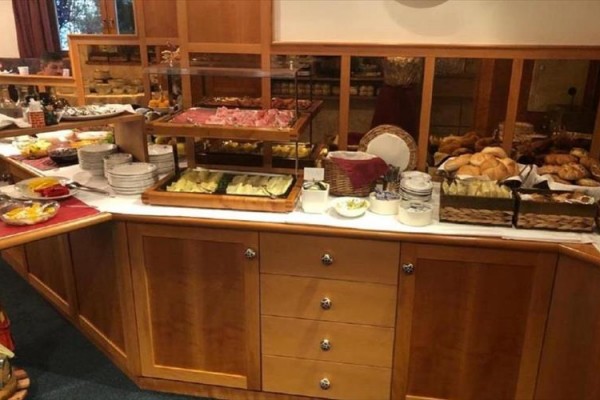 Bufetowy stół z różnymi rodzajami pieczywa, serów i wędlin.  