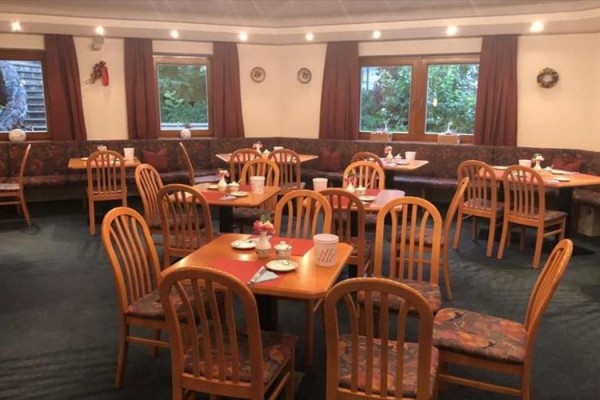 Restauracja z drewnianymi stołami i krzesłami, przygotowana na gości.