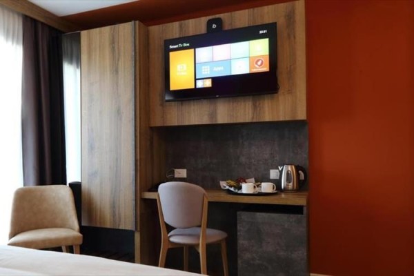 Pokój hotelowy z biurkiem, telewizorem i krzesłami.