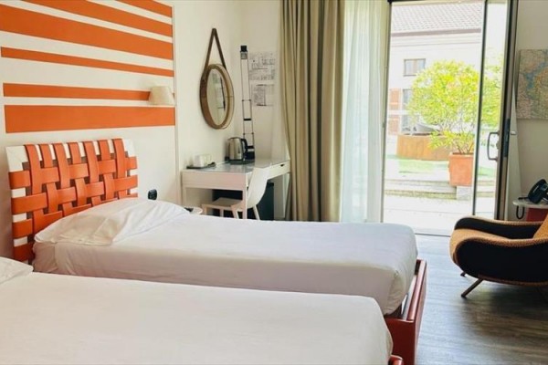 Nowoczesny pokój hotelowy z dwoma łóżkami, biurkiem i widokiem na ogród.