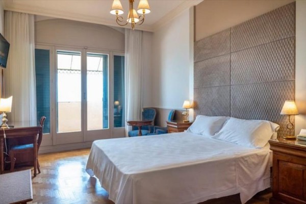 Elegancki pokój hotelowy z łóżkiem małżeńskim, biurkiem i francuskim oknem.