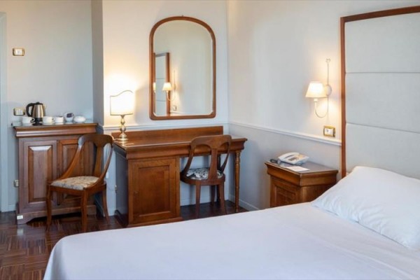 Pokój hotelowy z łóżkiem małżeńskim, biurkiem i kącikiem kawowym.