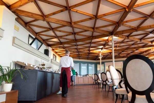 Eleganckie wnętrze restauracji z drewnianym sufitem i okrągłymi krzesłami.