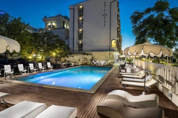 Hotelowy basen z leżakami i parasolami o zmierzchu.