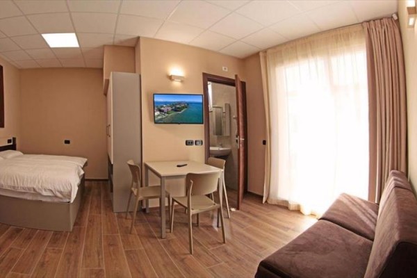 Nowoczesny pokój hotelowy z łóżkiem, kanapą, stołem i telewizorem na ścianie.