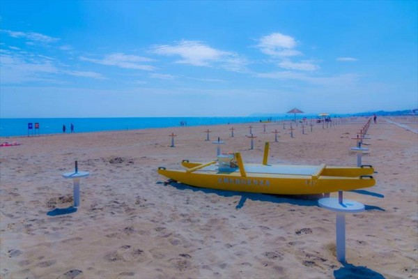 Żółta łódź ratunkowa na pustej piaszczystej plaży z widokiem na morze.