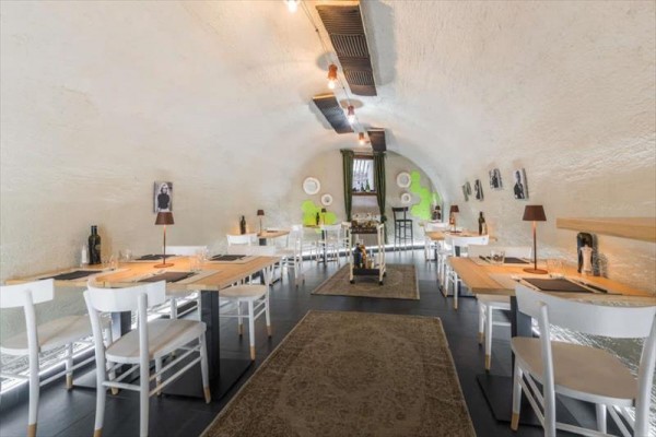 Stylowa restauracja z białymi krzesłami i drewnianymi stołami w sklepionej sali.