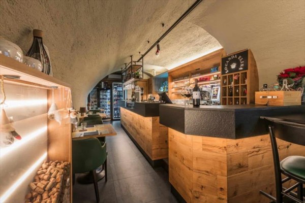 Nowoczesne wnętrze restauracji z drewnianym barem i stolikami.