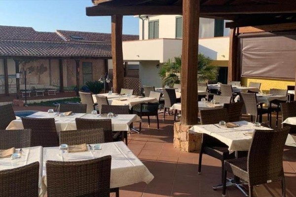 Zewnętrzny taras restauracji z nakrytymi stolikami i krzesłami.