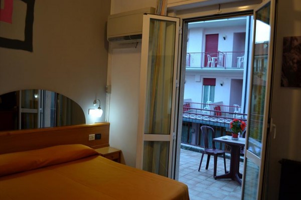 Sypialnia z wyjściem na balkon z widokiem na sąsiedni budynek.
