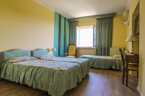 Przestronny pokój hotelowy z trzema łóżkami, oknem i meblami.