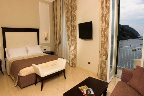 Elegancki pokój hotelowy z widokiem na morze przez drzwi balkonowe.