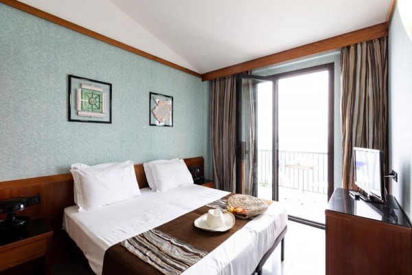 Pokój hotelowy z łóżkiem małżeńskim, stołem i balkonem.