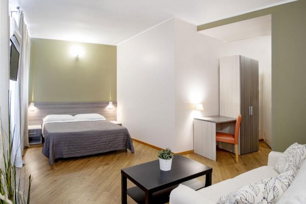 Nowoczesny pokój hotelowy z łóżkiem małżeńskim, biurkiem i kanapą.  