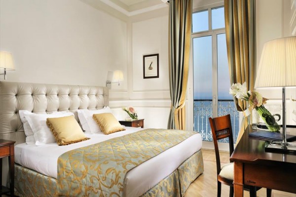 Elegancki pokój hotelowy z dużym łóżkiem i widokiem na morze.