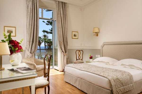 Elegancki pokój hotelowy z łóżkiem dwuosobowym i widokiem na morze.