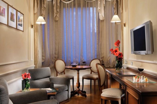 Elegancki salon z fotelami, stołem, telewizorem i kwiatami w wazonach.