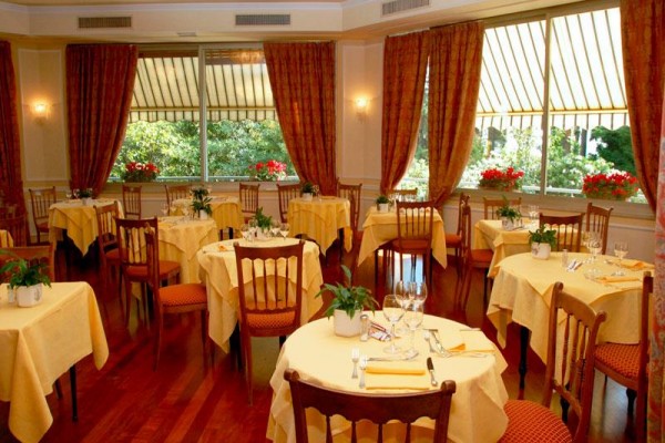 Restauracja z okrągłymi stolikami pokrytymi żółtymi obrusami i krzesłami.