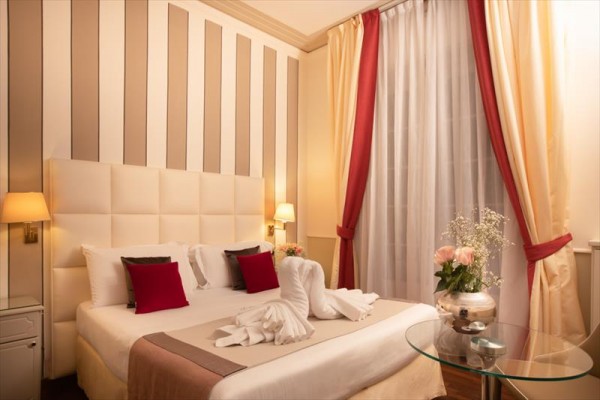 Elegancko urządzony pokój hotelowy z dużym łóżkiem, stylowymi zasłonami i poduszkami ozdobnymi.