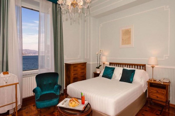 Luksusowy pokój hotelowy z łóżkiem i widokiem na morze przez okno.