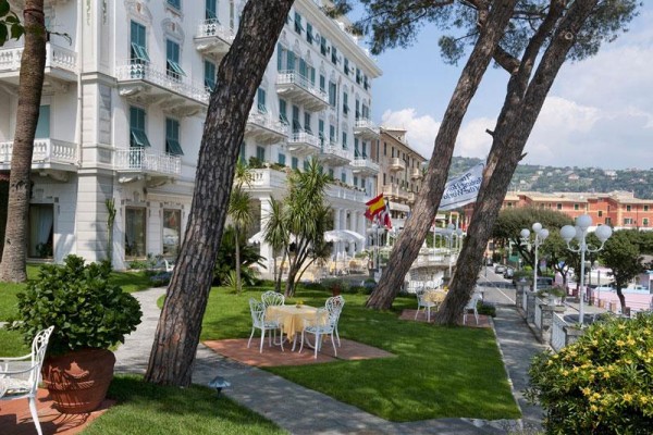 Elegancki hotel z tarasem i ogrodem z miejscem do siedzenia pod drzewami.