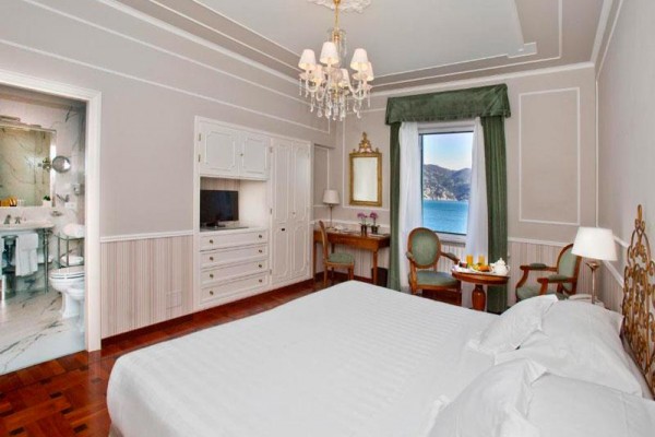 Elegancki pokój hotelowy z widokiem na morze, obok łazienki.