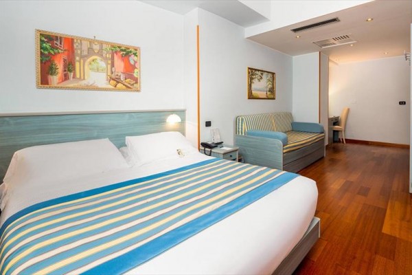 Pokój hotelowy z łóżkiem małżeńskim i sofą w paskowanym obiciu.